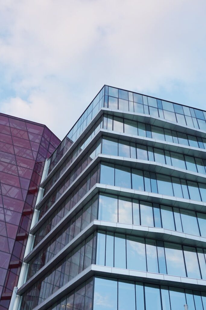 Contemporary urban architecture with glass and red facade against blue sky.